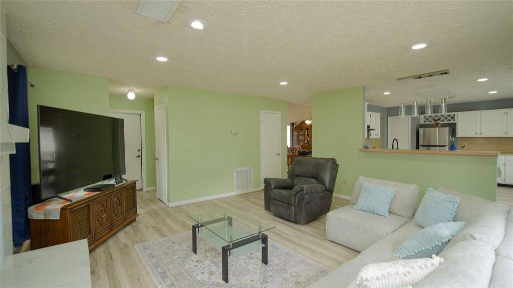 This living room features a modern design with a cozy fireplace and ample natural light. It has a neutral color palette, providing a welcoming space for relaxation.