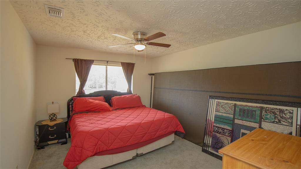 Cozy bedroom with a ceiling fan, featuring a window allowing natural light in.