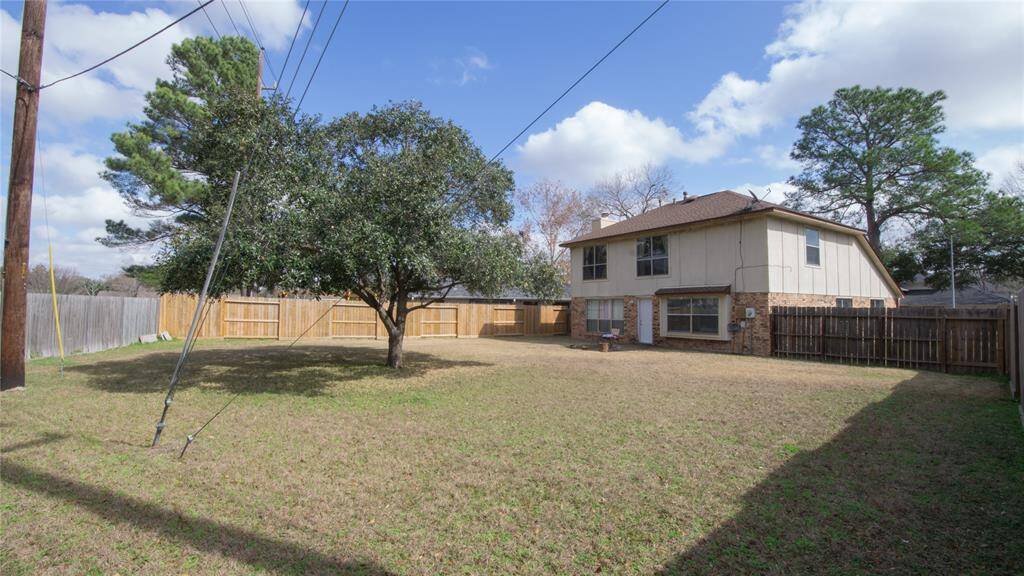 Spacious backyard with a large tree providing shade, surrounded by a wooden fence for privacy. Suitable for outdoor activities or gardening.