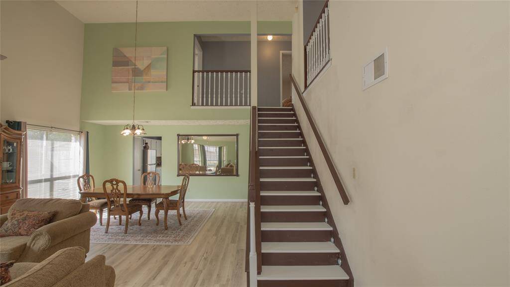 The first floor showcases a spacious, open-concept formal living and dining area with high ceilings. It features a staircase leading to an upper level, recent new luxury flooring, and large windows that allow plenty of natural light. The dining area is conveniently located between the kitchen and formal living room and great for entertaining guest.