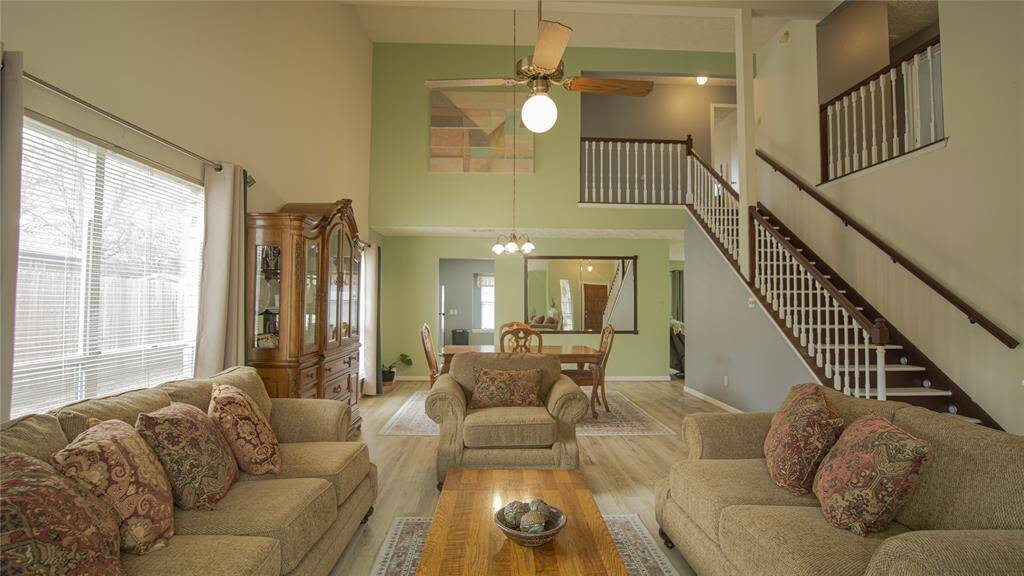 The first floor showcases a spacious, open-concept formal living and dining area with high ceilings. It features a staircase leading to an upper level, recent new luxury flooring, and large windows that allow plenty of natural light. The dining area is conveniently located between the kitchen and formal living room and great for entertaining guest.