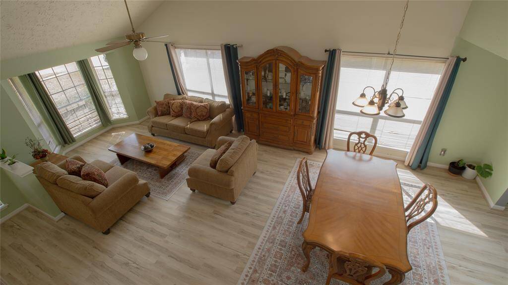 This photo showcases a bright, open-concept living and dining area with high ceilings. It features large windows, light wood flooring, and tasteful furniture. The space is inviting and well-lit, ideal for family gatherings.