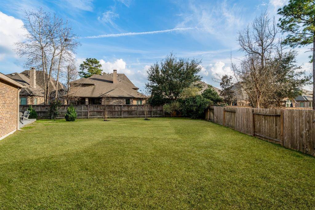 Spacious backyard with well-maintained lawn, wooden fencing for privacy, and mature trees providing shade. Ideal for outdoor activities and relaxation for all the family.