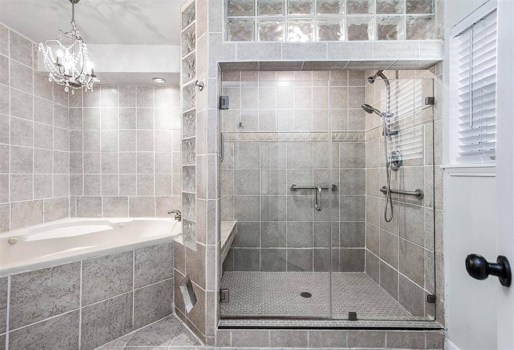 Primary Bath is a Spa-like Oasis with Stand/Sit Shower w/Glass Door, Whirlpool Tub, Tile, Glass Bricks & beautiful Chandelier!