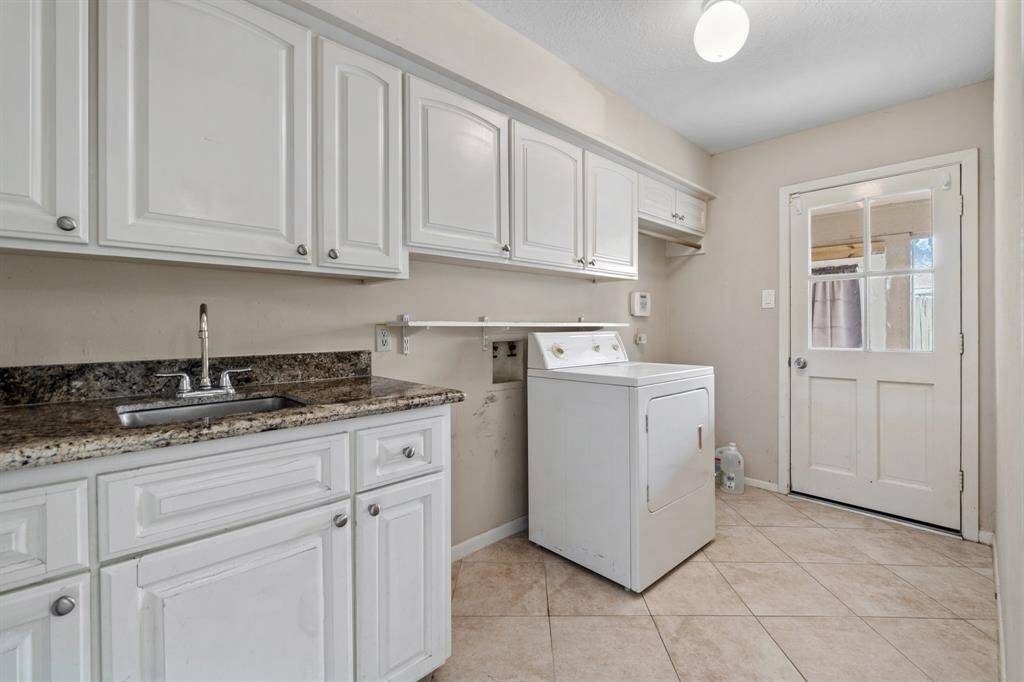 Utility Room (In-House) features cabinetry and sink. Provides access to the back patio area and built-in garage passenger door.