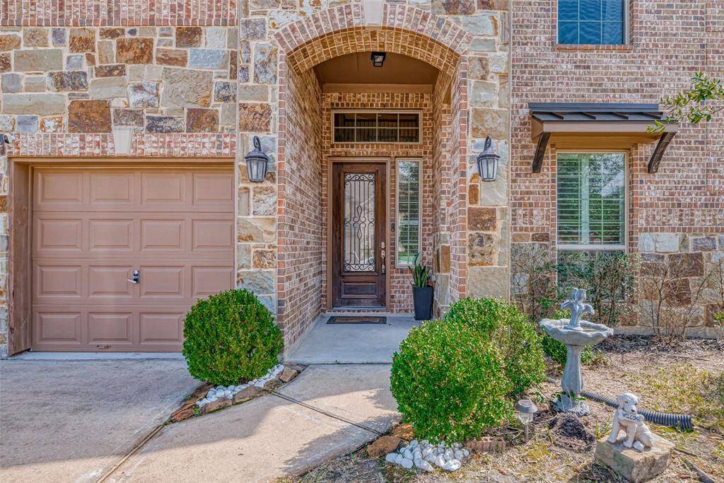 Gorgeous brick and stone facade with a welcoming front entrance, featuring a decorative door and sidelights. The landscaped entry includes greenery and attractive exterior lighting enhancing the home's curb appeal.