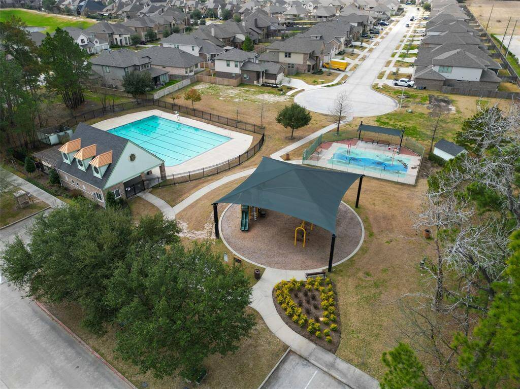 This aerial photo shows a community area with two pools, and a shaded playground. The neighborhood features tree-lined streets, and well-maintained landscaping, providing a family-friendly environment.