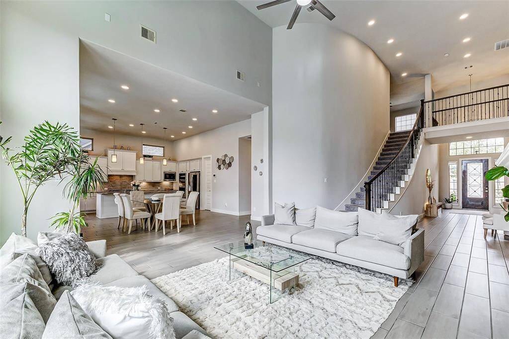 This spacious and modern home features an open floor plan with high ceilings, a sleek kitchen with contemporary fixtures, and a cozy living area. The grand staircase leads to a second level, and large windows fill the space with natural light, creating an inviting and airy atmosphere.
