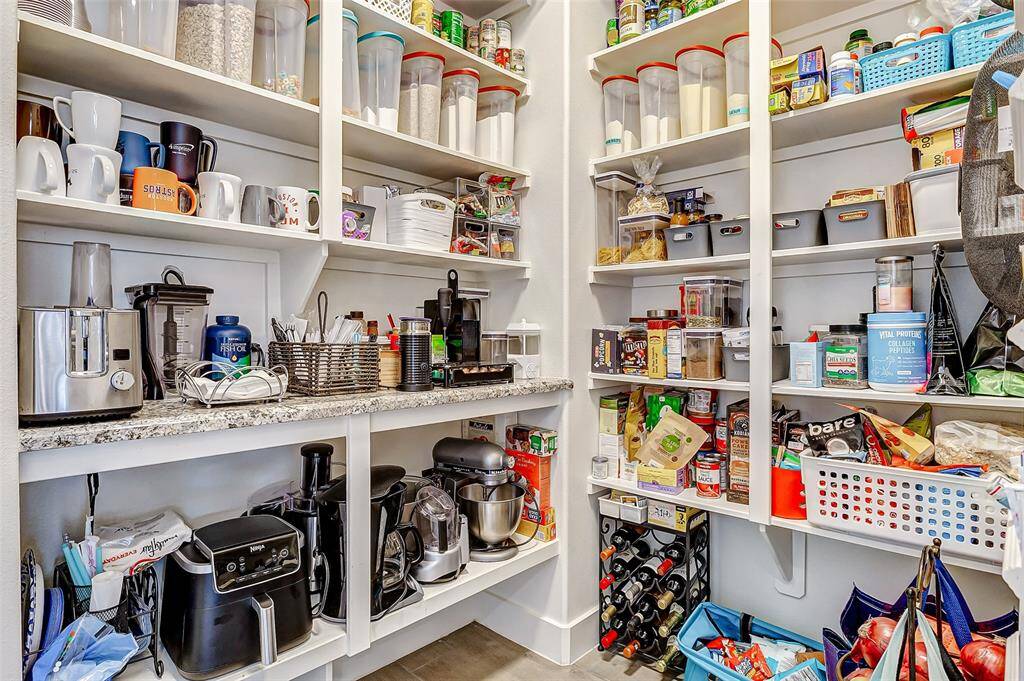This photo showcases a well-organized pantry with ample shelving, featuring a variety of kitchen appliances, storage containers, and an assortment of food items. The space is efficiently utilized with a mix of open shelving and baskets, providing convenient access and storage.
