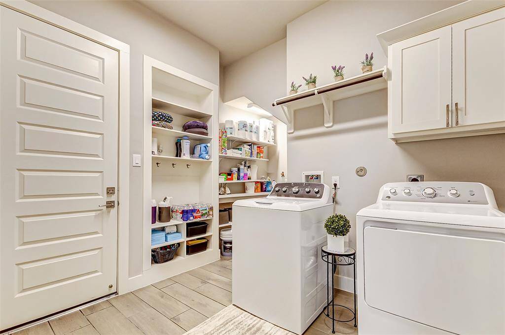 This well-organized laundry room features ample shelving for storage, and a clean, neutral color palette. It offers practical built-in cabinets and a convenient folding counter, perfect for efficient household chores.