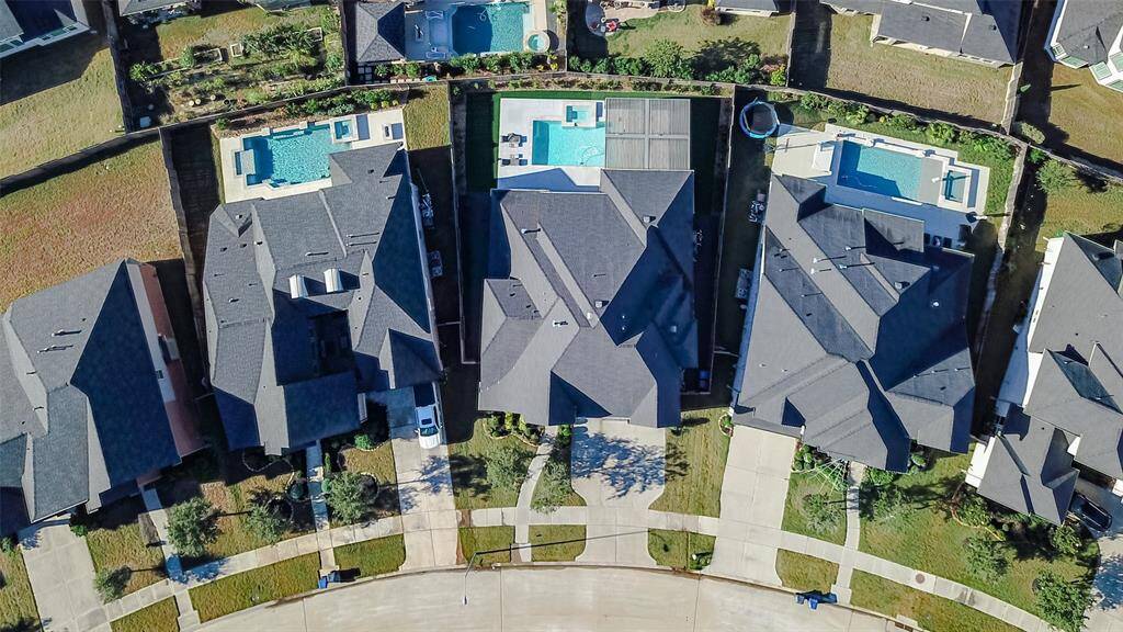Suburban neighborhood with well-maintained homes, each featuring a backyard pool. The houses are arranged along a curved street, providing a spacious and organized community layout.