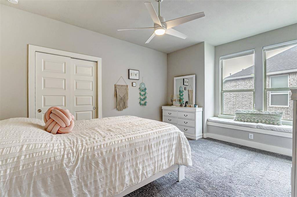 Secondary bedroom upstairs with seating area close to the window.