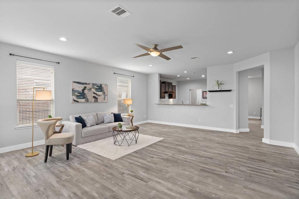 The spacious gathering room is a standout feature, enhanced by beautiful laminate wood flooring that adds warmth and elegance. This inviting space offers a seamless flow from the gathering area through the dining room and into the kitchen, creating an open and connected atmosphere perfect for both relaxation and entertaining.