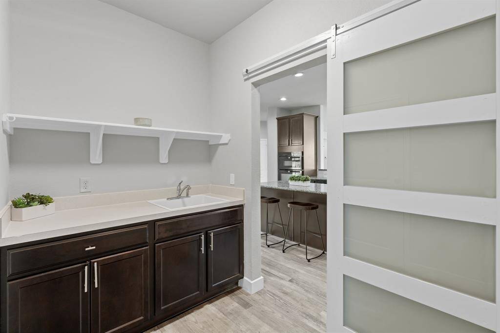 The laundry room is more than just a functional space; it’s a perfect blend of thoughtful design and convenience, featuring a utility sink and a stylish barn door that adds charm and practicality to the room.