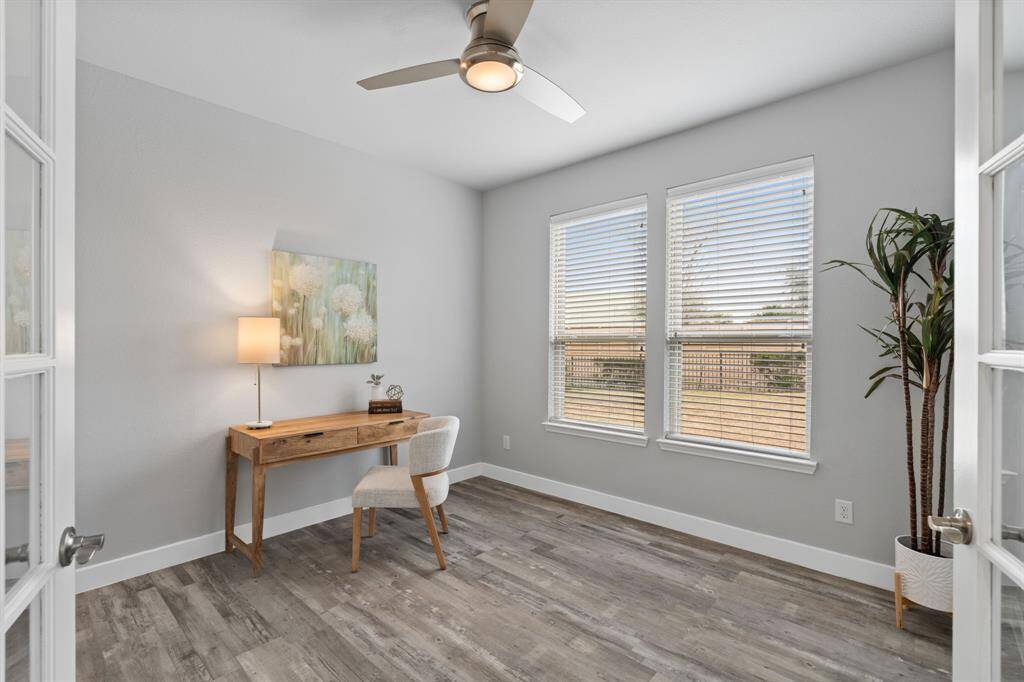 Study with French Doors showcases a bright and inviting space with two large windows, letting in plenty of natural light. It features sleek wood flooring, a modern ceiling fan. Ideal for a home office or quiet reading space.