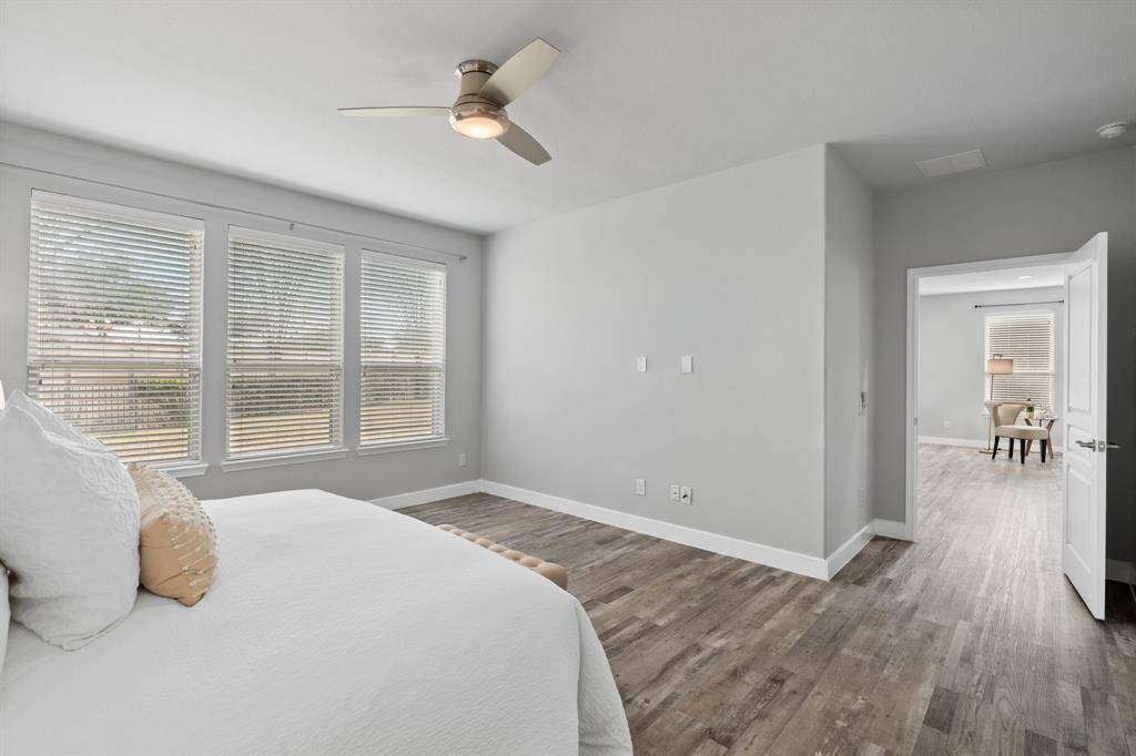 The bright and spacious Primary Bedroom is filled with natural light from large windows and soft, light-colored walls. Featuring wood-style flooring and a modern ceiling fan, it’s the perfect place to unwind after a long day of pickleball.