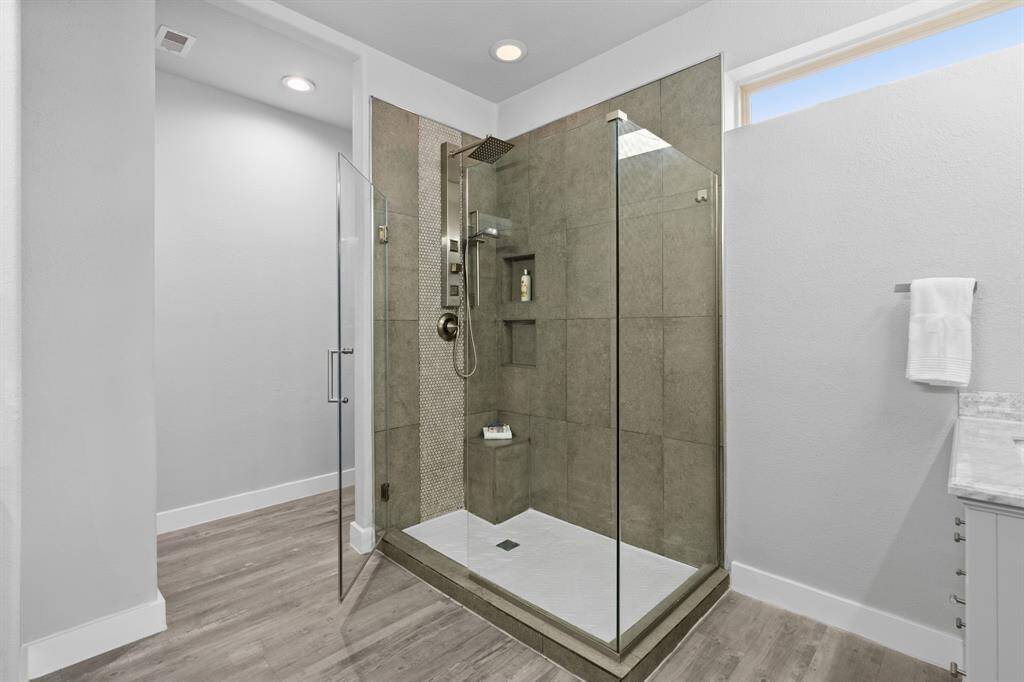 Step into the shower and indulge in a spa-like retreat, where elegant tile flooring sets the stage for relaxation. Enjoy the luxury of both a handheld and rain shower head, complemented by a built-in bench—perfect for unwinding as the day's stresses wash away.