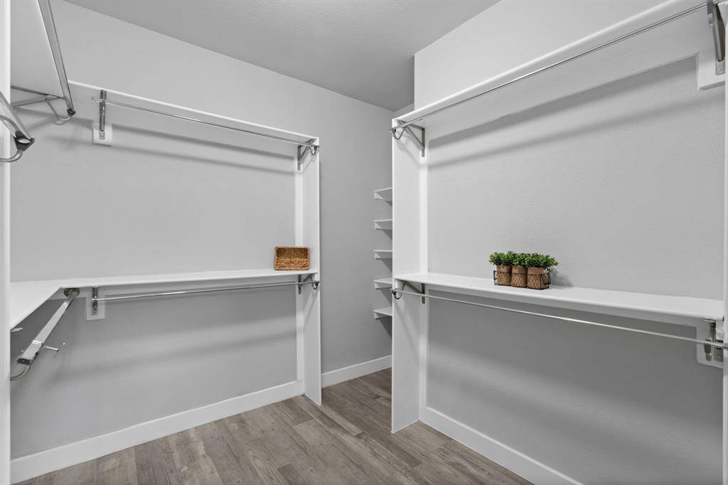 This spacious walk-in closet has been thoughtfully remodeled to maximize storage, offering abundant hanging space, custom shelving, and a sleek, modern design. Light-colored walls and flooring enhance its bright, open feel, creating the perfect space for effortless organization of clothing and accessories.