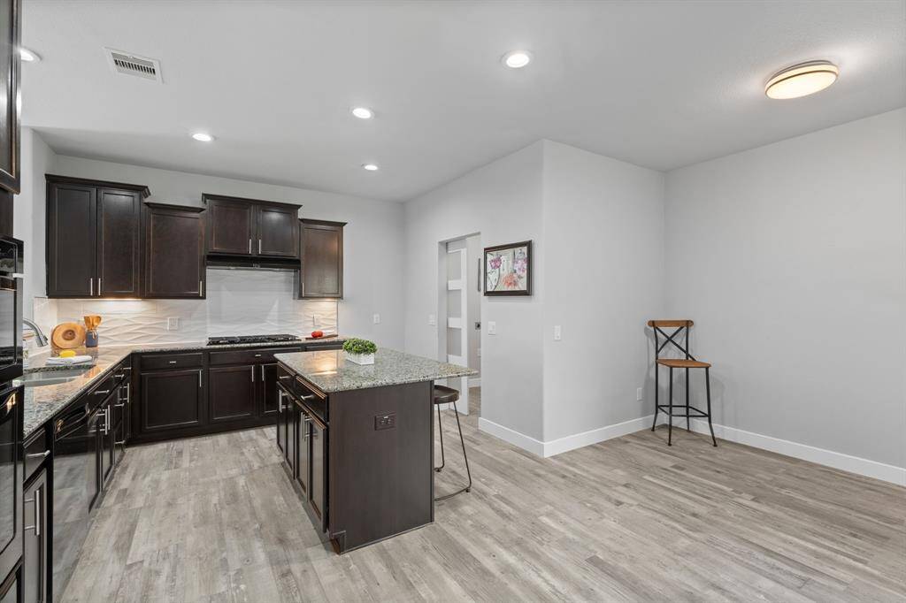 This kitchen is the heart of the home, combining both style and functionality for all your culinary endeavors. Gleaming granite countertops, a chic white backsplash, and dark cabinetry with light flooring create a stunning contrast, while under-cabinet lighting adds a touch of elegance. With ample counter space, it’s perfect for baking bread or cookies and preparing your favorite meals.