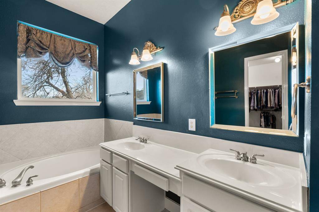 The primary bathroom has a bath tub, shower, and dual sink vanity.