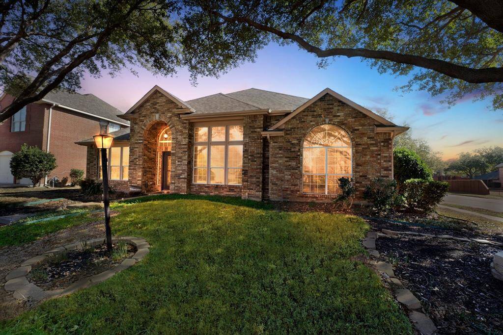 Charming brick home with large windows and a welcoming entrance, nestled between mature trees and well-maintained landscaping. Ideal for those seeking a blend of natural beauty and curb appeal.