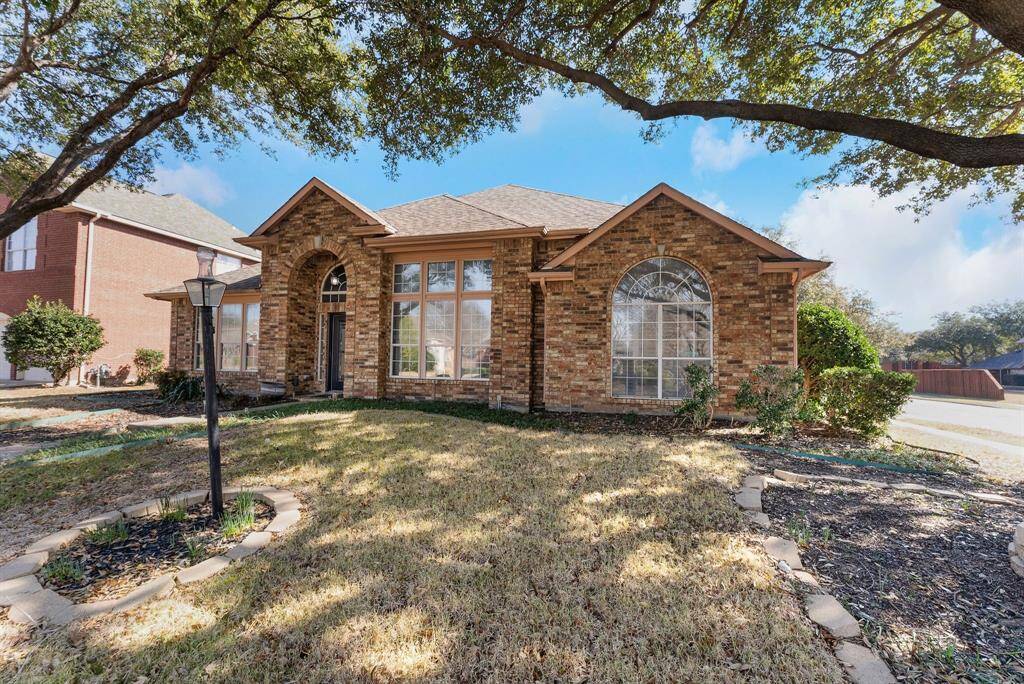 Charming brick home with large windows and a welcoming entrance, nestled between mature trees and well-maintained landscaping. Ideal for those seeking a blend of natural beauty and curb appeal.