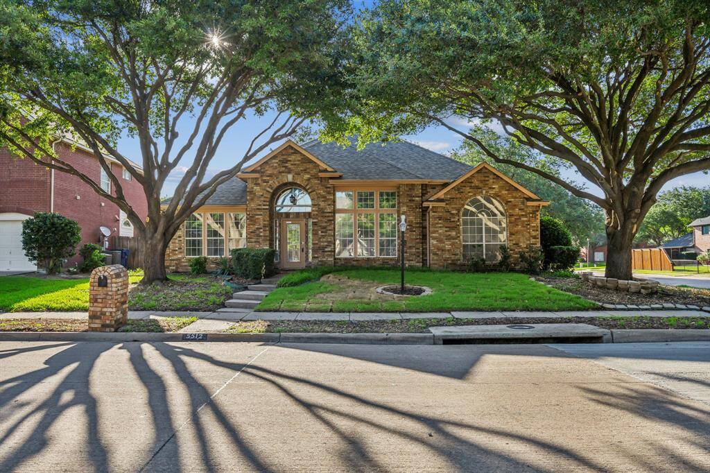 Charming brick home with large windows and a welcoming entrance, nestled between mature trees and well-maintained landscaping. Ideal for those seeking a blend of natural beauty and curb appeal.