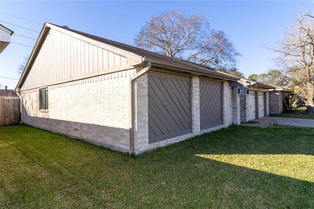 This photo features a single-story home with light brick siding and a sloped roof. It has a two-car garage with decorative doors and a well-maintained lawn. The backyard is fenced, providing privacy. The ROOF is NEW. It was changed on 03/01/2025