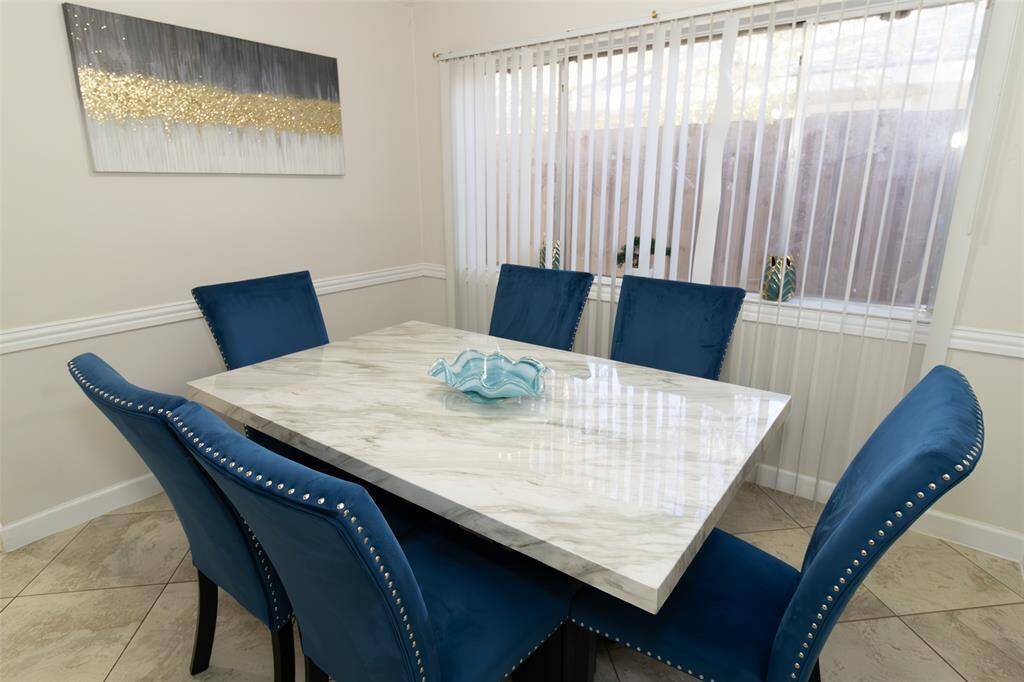 The room features a large window with vertical blinds, offering natural light.