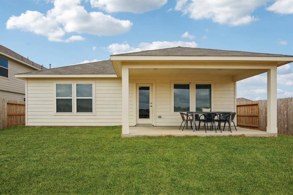 Covered back porch with space for a dining table and grill.