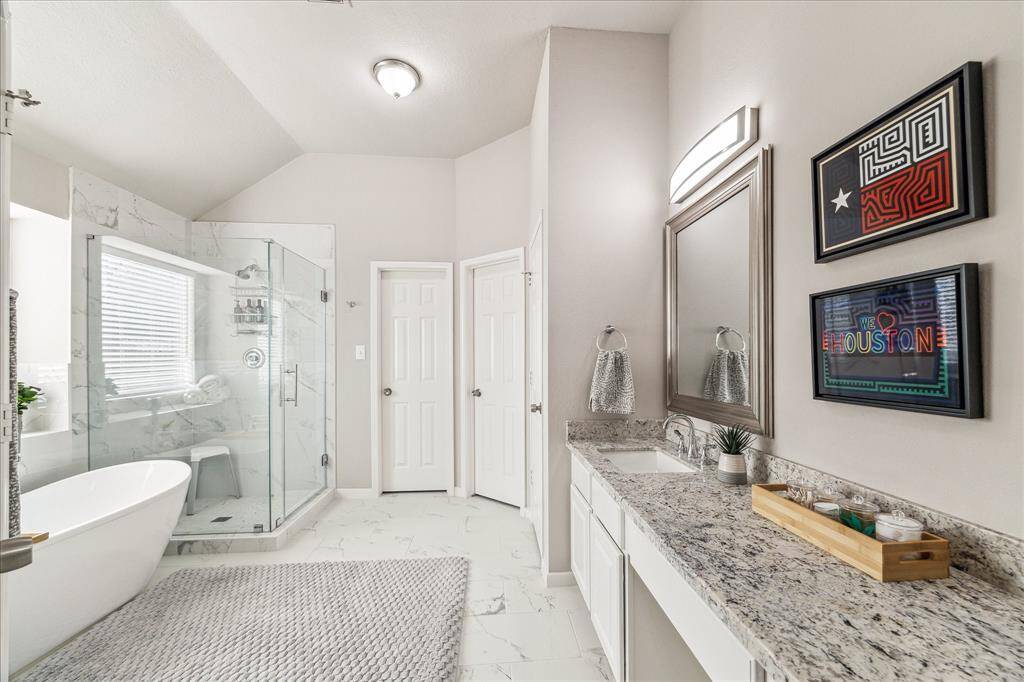 Elegant updated bathroom featuring dual sinks, spacious vanity, stunning granite countertops, and sleek tile floors.