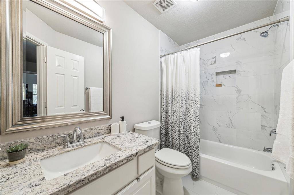 Stylishly updated secondary bathroom with elegant tile and granite countertops.