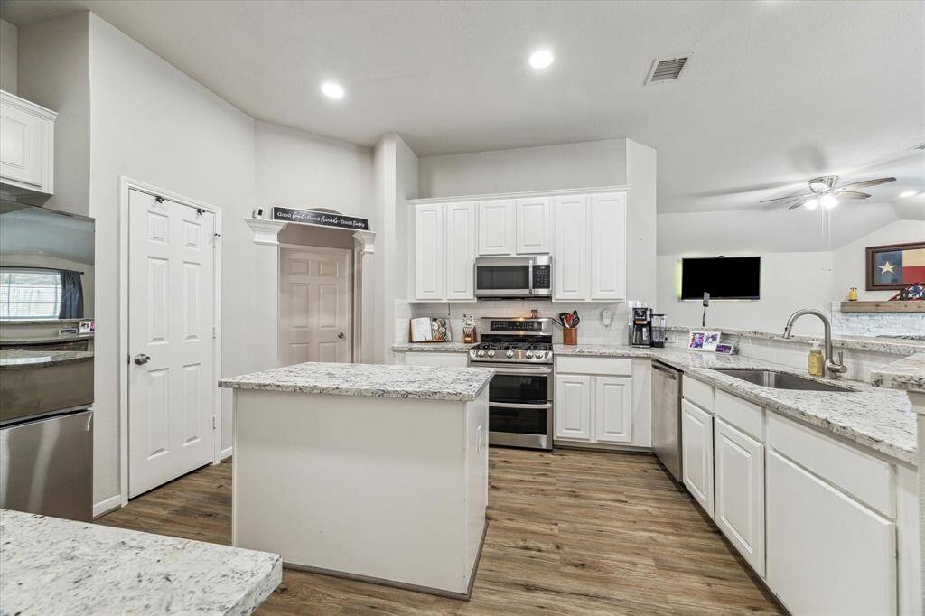 Stylish island kitchen featuring elegant granite countertops, recessed lighting and modern stainless steel appliances.