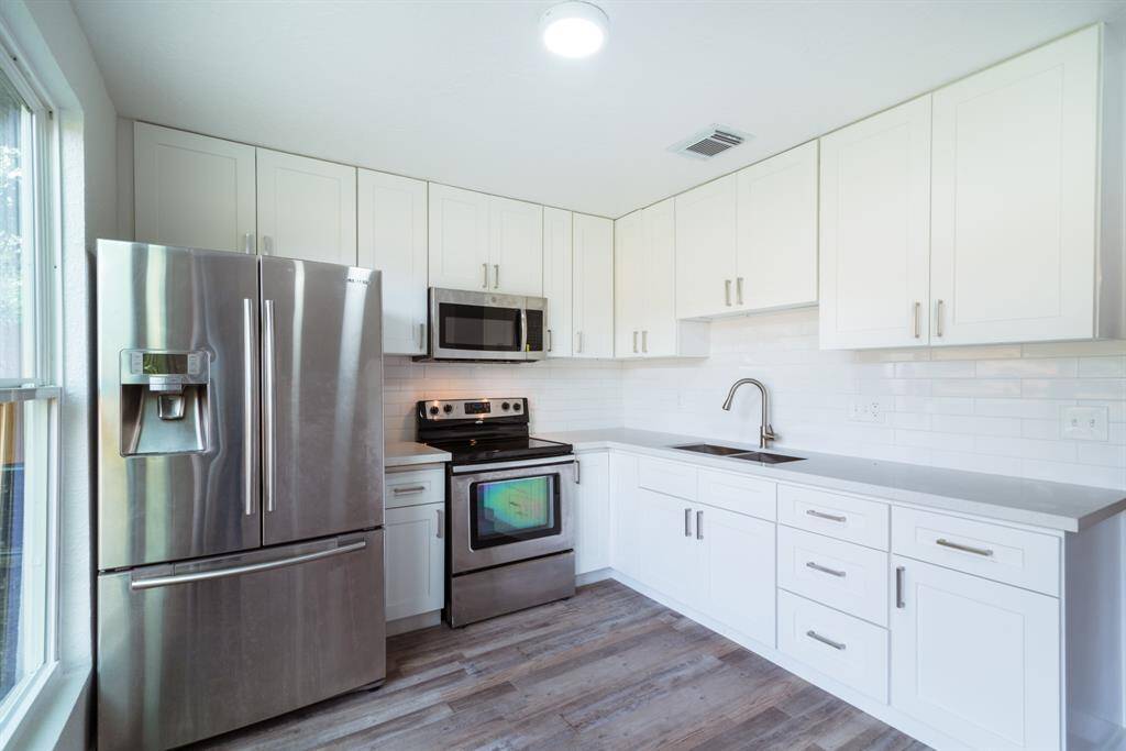 This photo shows a bright, spacious room with freshly painted white walls and wood-style flooring, offering a clean and modern feel. The open layout provides flexibility in design and usage.