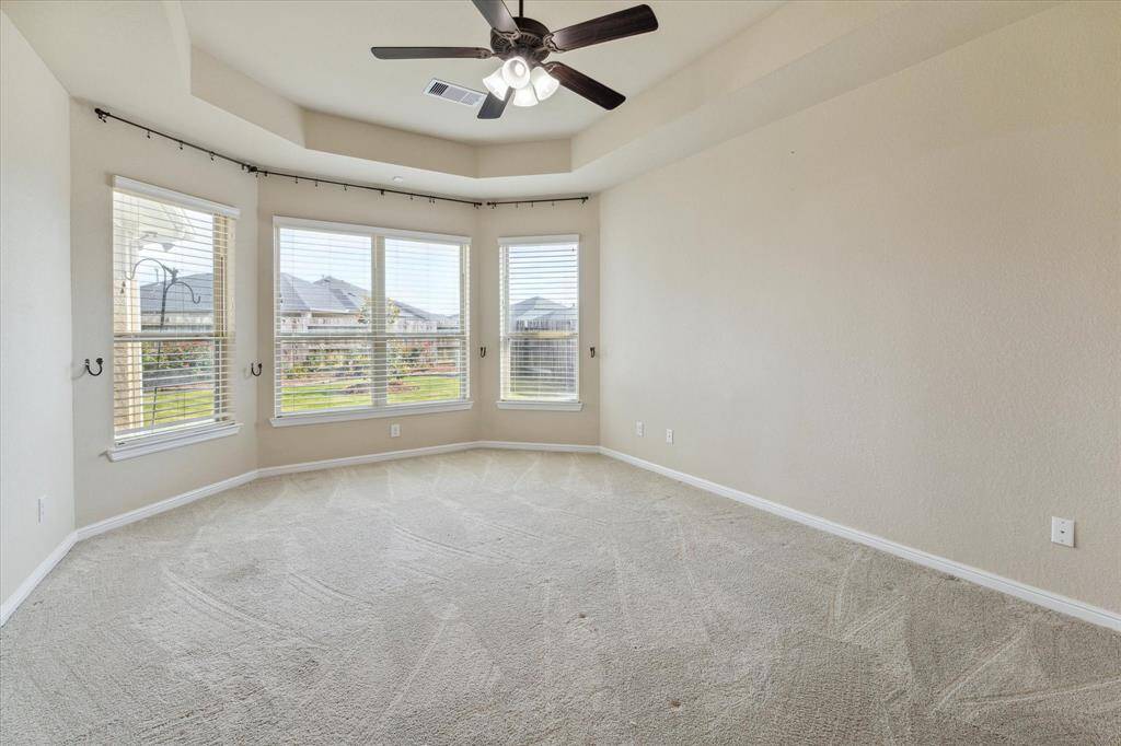 Large Primary Suite with four bay windows overlooking the backyard.  The room features a tray ceiling and lighted ceiling fan.