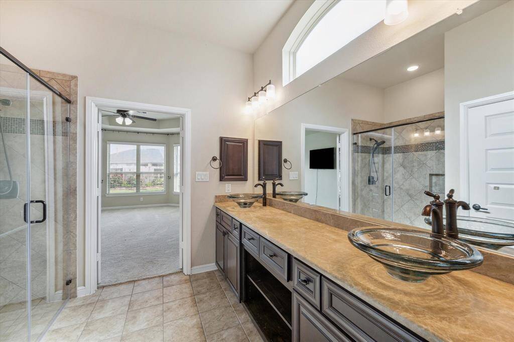 Primary bathroom has vessel sinks, bilt in medicine cabinets, storage shelves between the two sinks, and a window the sinks to let in tons of natural light.
