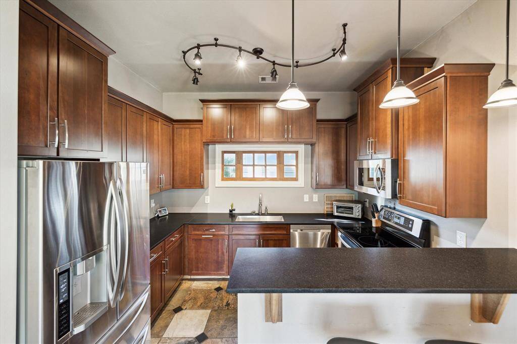 The beautifully appointed windowed kitchen includes breakfast bar seating, gleaming wood cabinetry and honed granite countertops. The upscale stainless steel appliances include a glass-top range, French door refrigerator, dishwasher and built-in microwave.