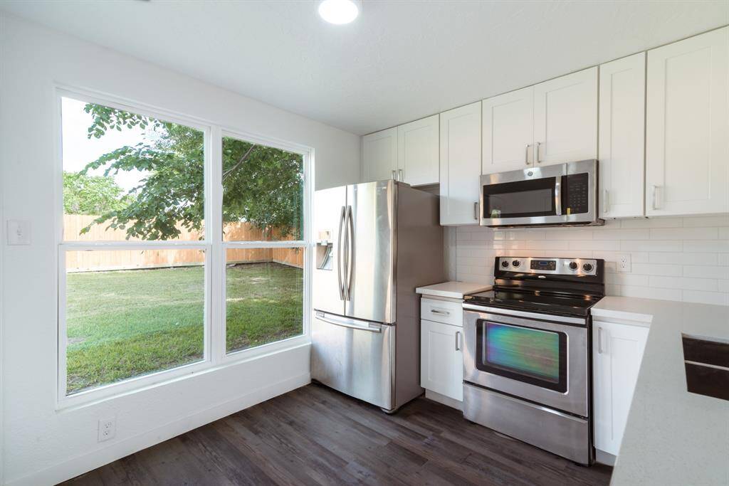 This bright room features fresh white walls, a large window offering plenty of natural light, and sleek wood flooring, creating a modern and inviting space.