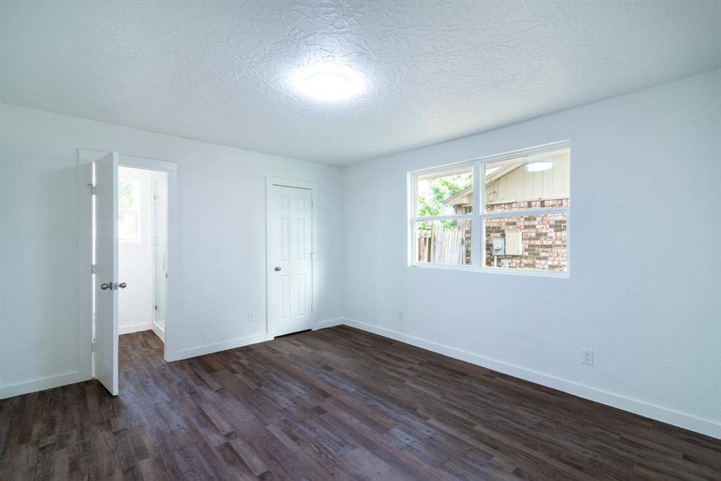 Bright, open room with fresh white walls and wood-style flooring, featuring a door with a window that brings in natural light.