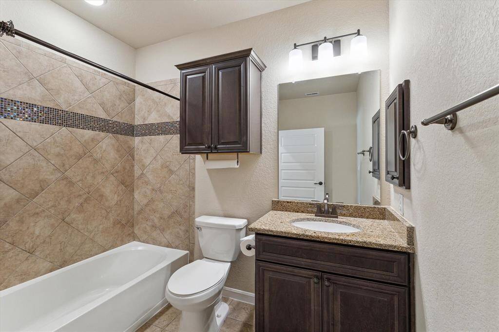 Quest bathroom has decorative tile trim, extra cabinet over the toilet, built in medicine cabinet and granite countertop.
