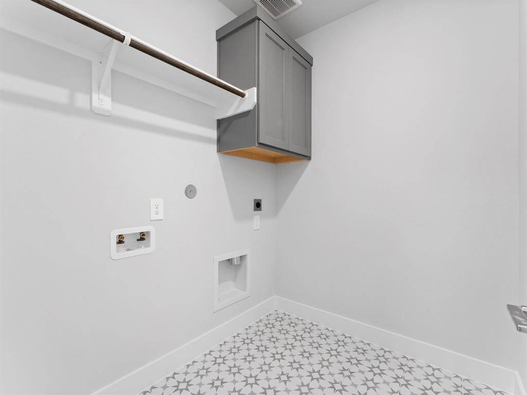 Utility Room with Patterned Tile Flooring, Washer and Dryer Connections, Storage Cabinet, and Hang to Dry Bar.