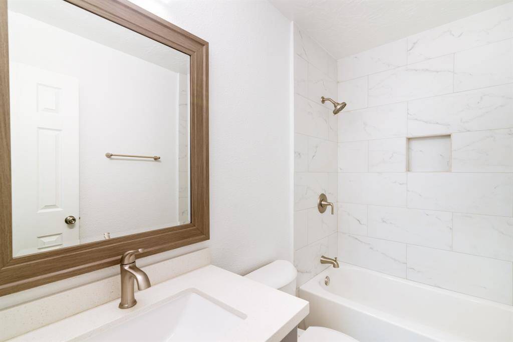 This bright room features wood flooring, a large window for natural light, and access to an adjoining bathroom. The clean white walls create a fresh, open feel.