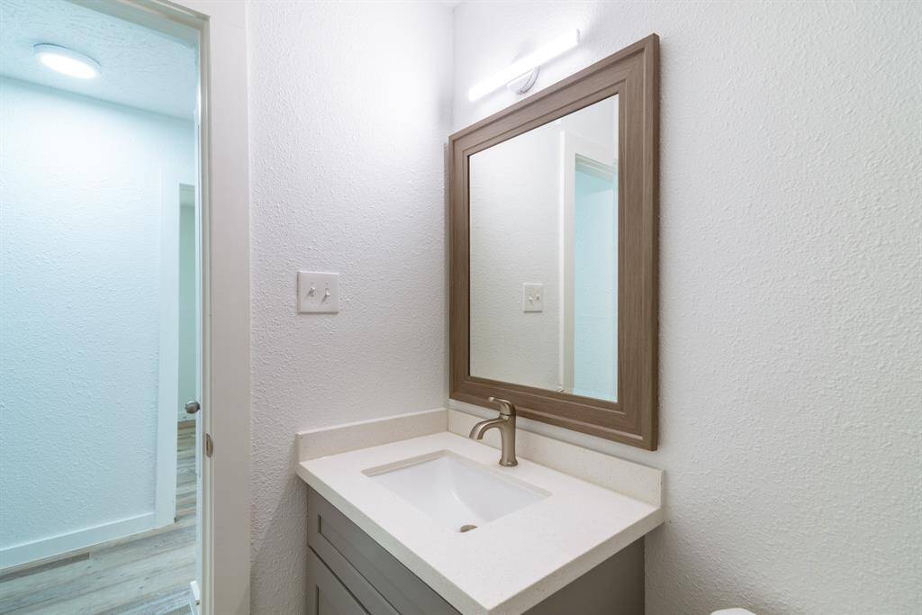 This is a bright, freshly painted room with dark wood flooring, featuring a closet and a doorway leading to a bathroom.