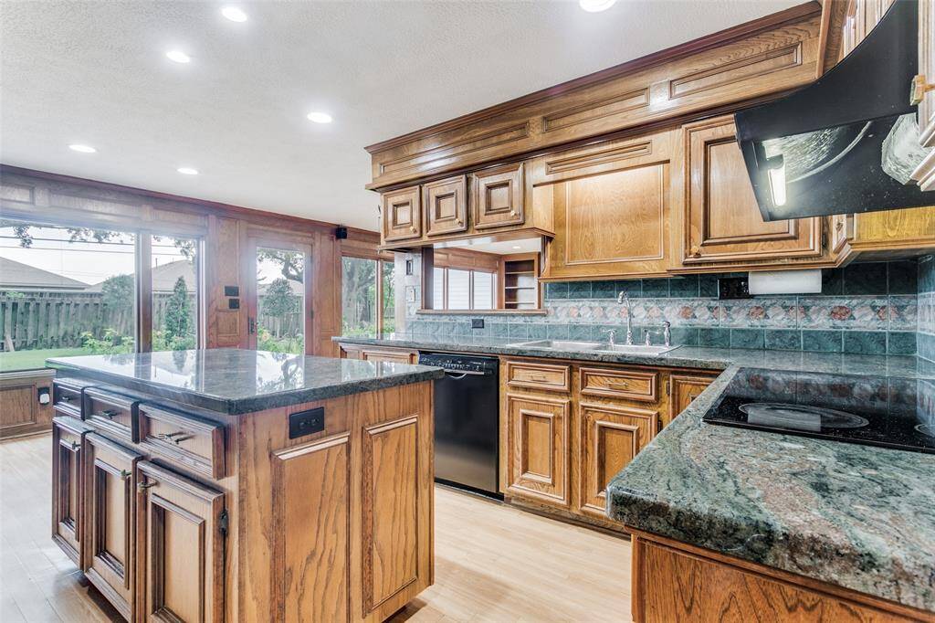 Spacious kitchen features natural wood cabinetry, granite countertops, deep sinks and high end appliances. Ample storage and central island with plenty of natural light. Bosch dishwasher installed in 2022 .