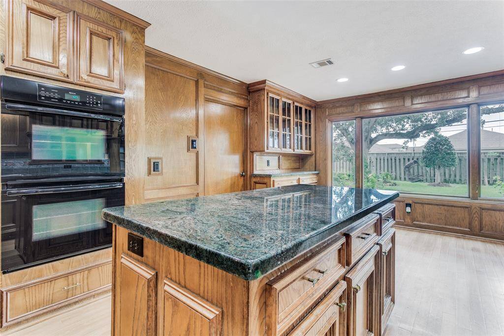The large island includes an electrical outlet and cut out for microwave. Jenn Air double ovens installed in 2023.