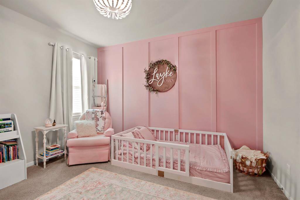This cozy bedroom #1 features a soft pink shiplap accent wall. Plenty of room for several pieces of furniture, with a charming chandelier/ceiling fan, adding a touch of elegance.