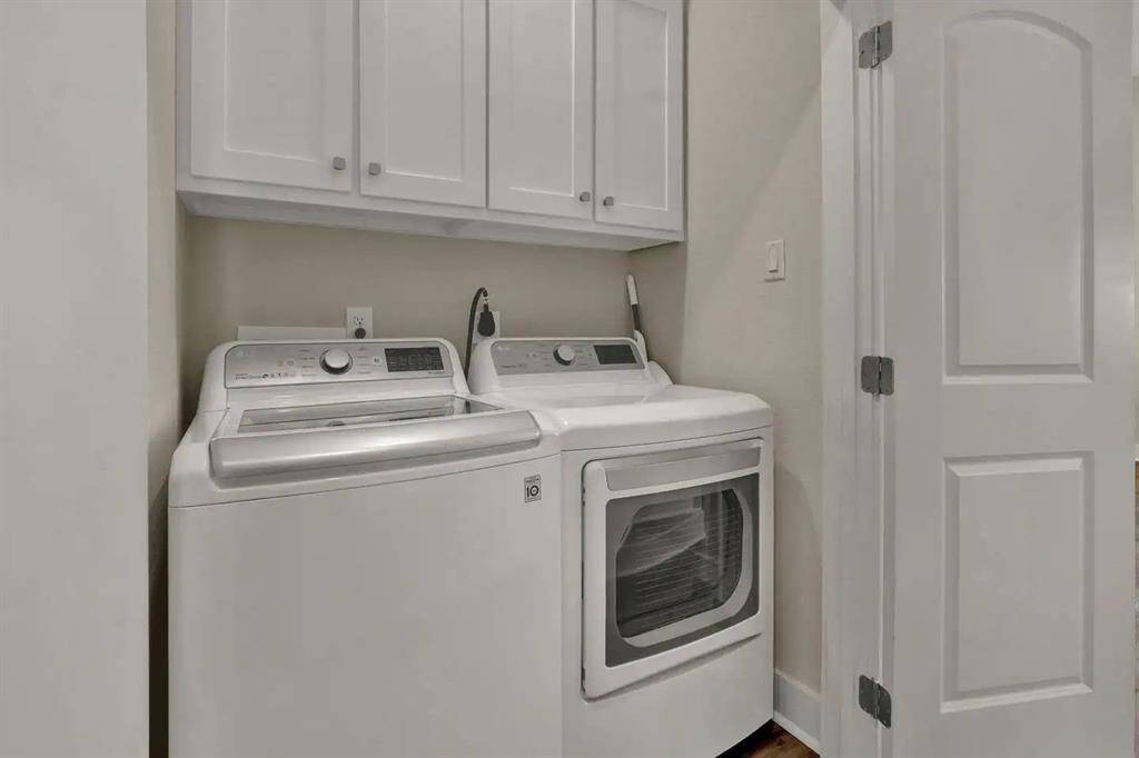 Full laundry in hallway with supplies in cabinets above