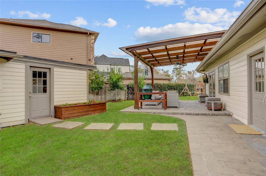 View of the back patio space from the private driveway. The door to the left is one of two storage sheds attached to the garage.