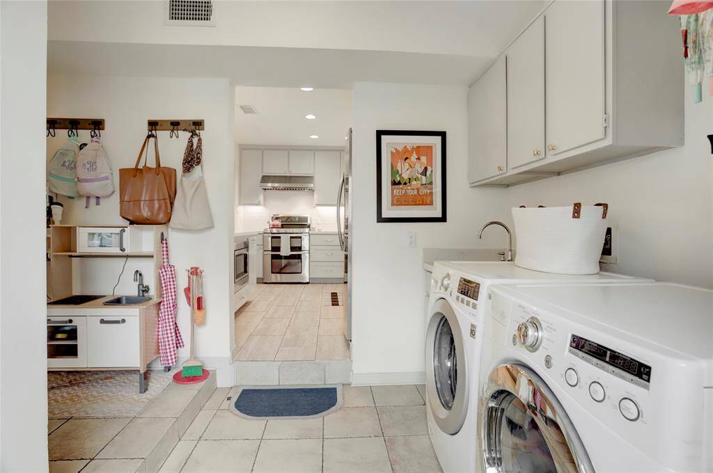 Located between the back patio and kitchen sits a spacious utility room with storage options and a sink.