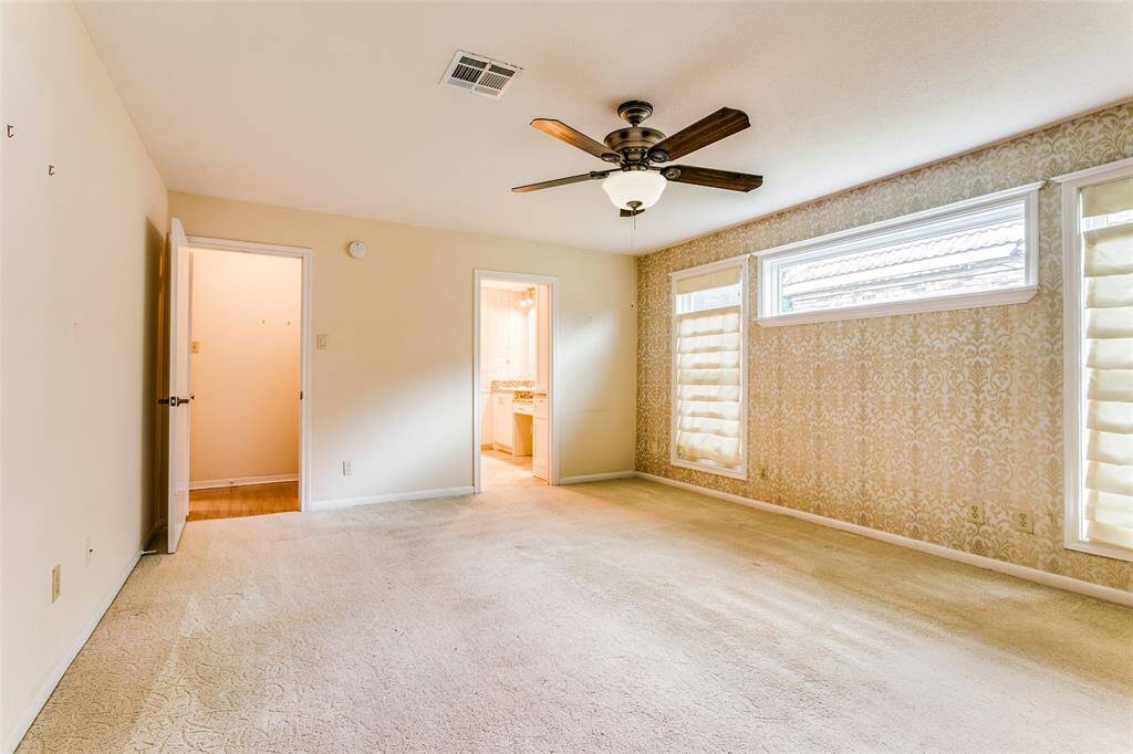 This is a well-lit, spacious primary bedroom featuring a pocket door leading to an adjoining primary bathroom.
